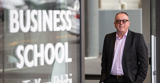 A man standing at the entrance to the business school 