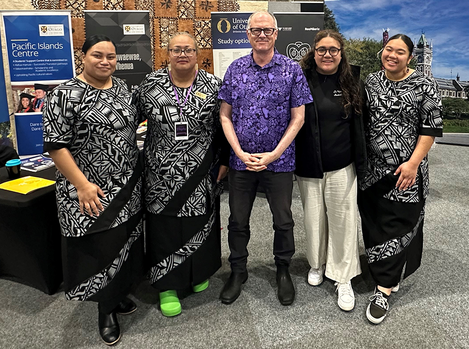 four women and a man in front of a uni display at an event