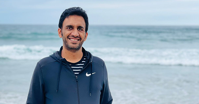 A man standing at the beach in front of water 