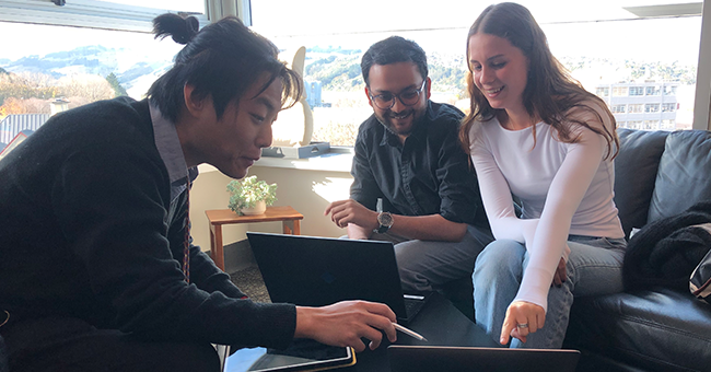 Three people chatting around a laptop 