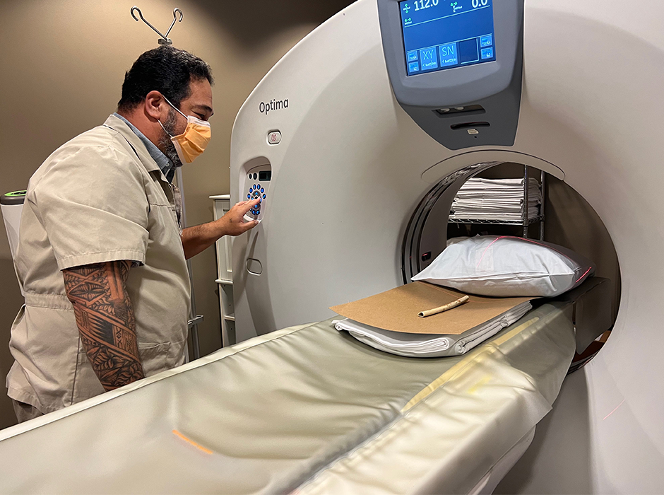 A man putting a bone flute through a scanning device