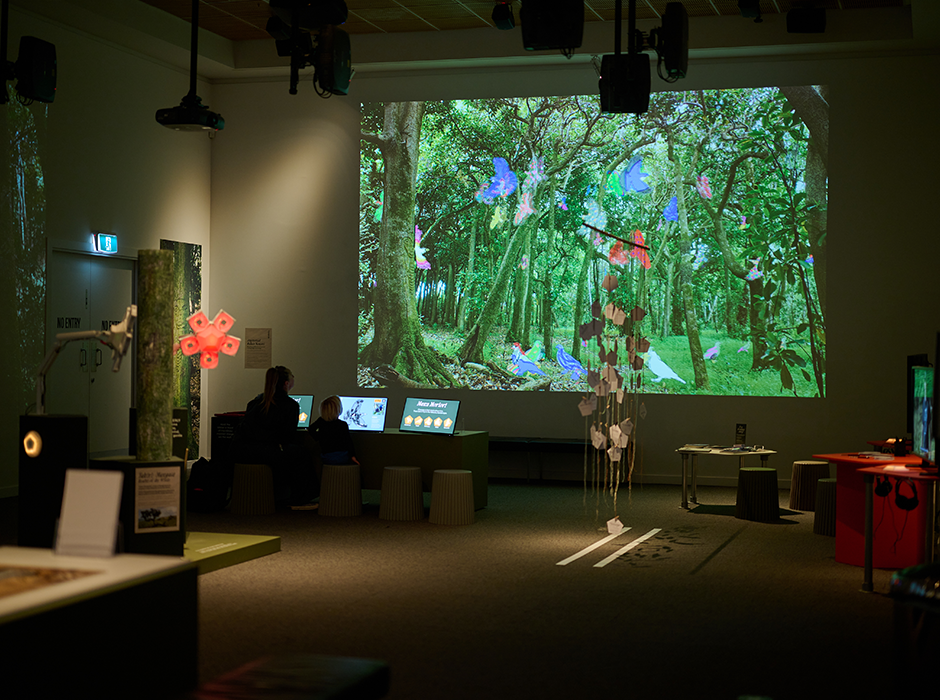 A large image of trees being projected on the wall of a darkened room 