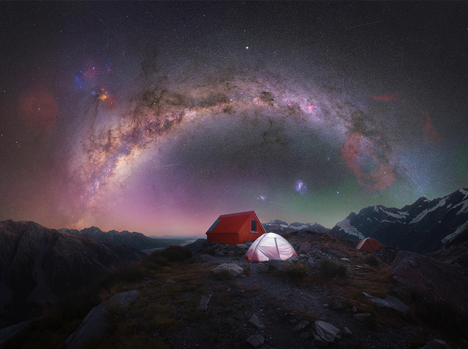 A starry sky above a darkened landscape with tents