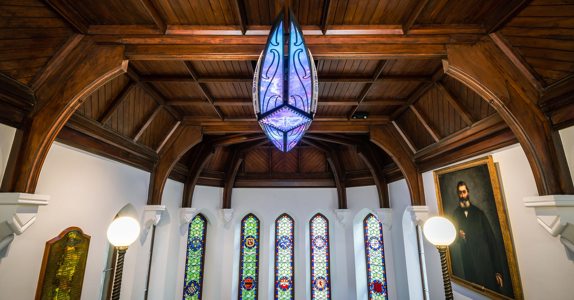 Ornate wooden ceiling with celestial waka artwork, and stained glass windows, in the University's registry (Clocktower) building.