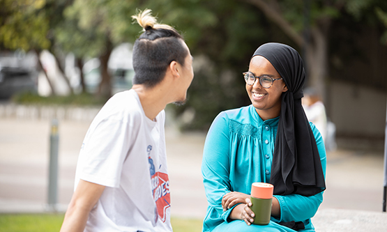 A young man and a woman talking and smiling in a landscaped outdoor area