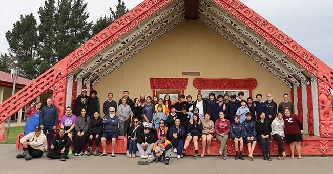 Many people sitting and standing at a marae