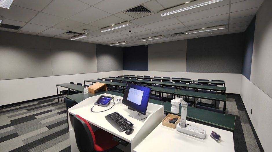 View of Burns 4 seminar room righthand from front, with a computer on a lectern and tables and chairs in rows