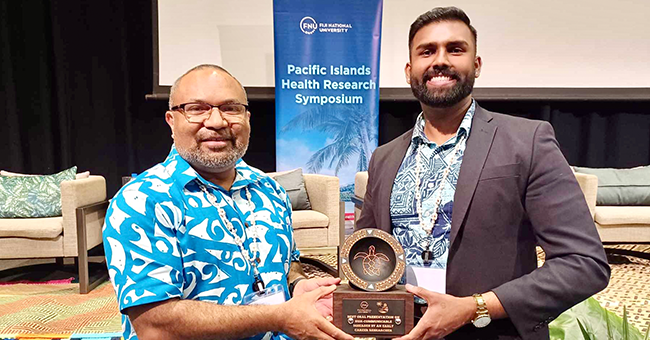 One man gifting an award to another, both are smiling