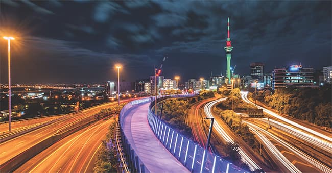 Auckland city at night, time-lapse image showing car lights on the motorway