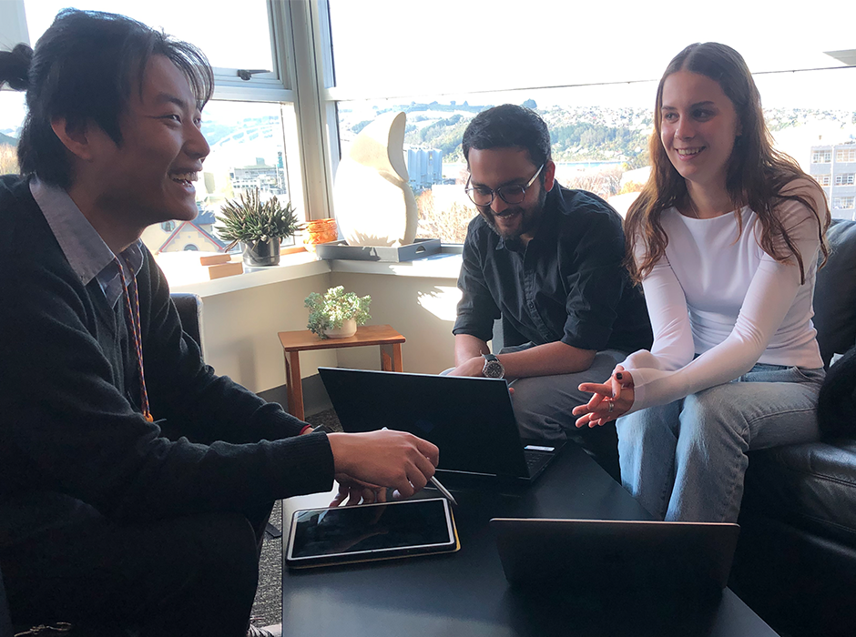 Three marketing students chatting around a laptop 