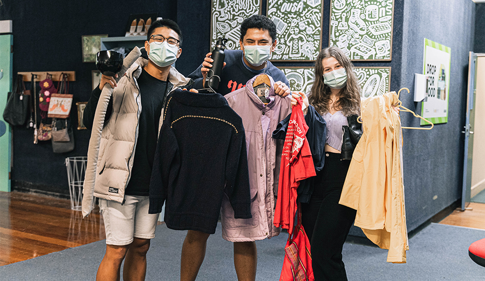 Three students in masks showing off their clothing finds at the Te Oraka store