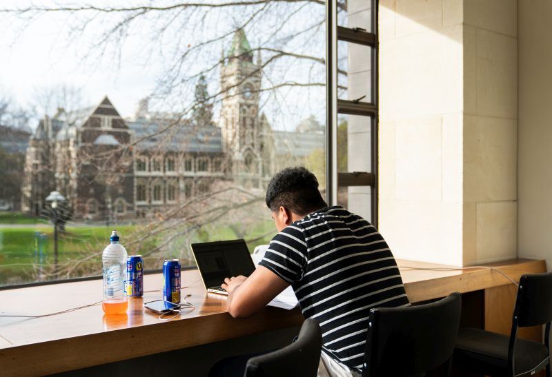 student studying on laptop with clocktower in background