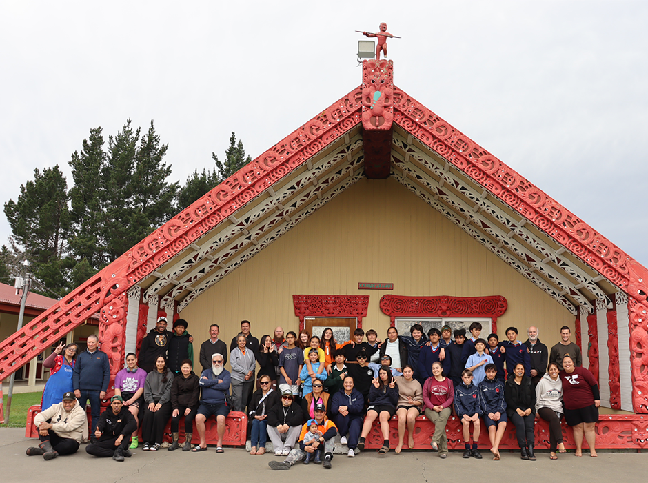 Many people sitting and standing at a marae