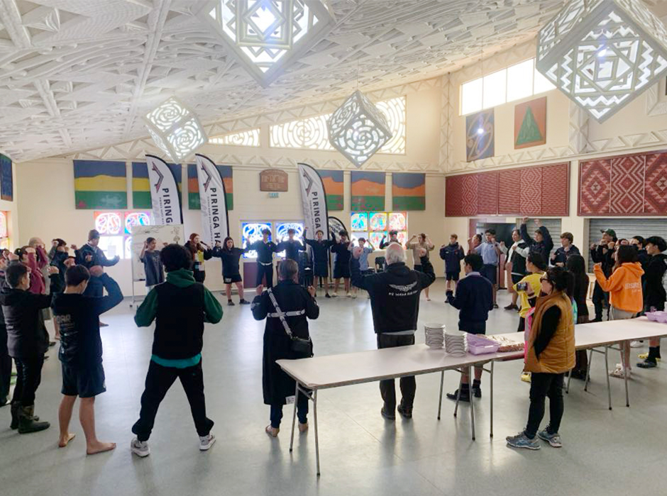 Many people standing in a large circle in a room playing a game