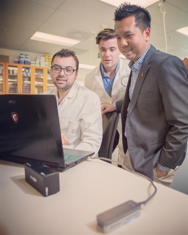 A photo of Dr Aung and two students doing third-generation long-read Nanopore sequencing