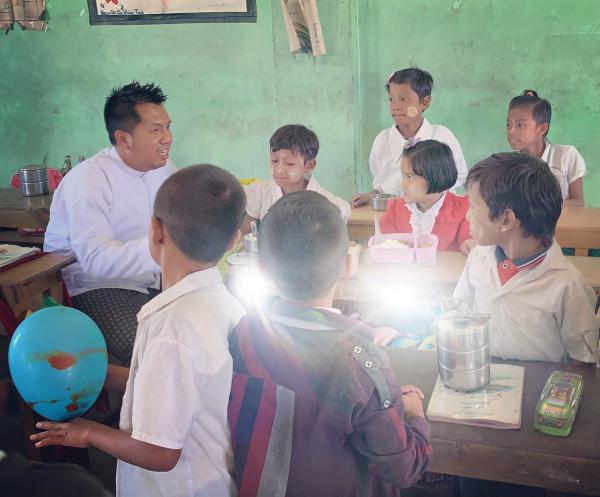 A photo of Dr Aung talking with children in a classroom