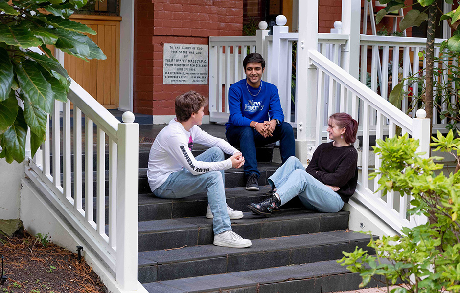 Three students sitting on the steps to the entrance of St Margaret's College.