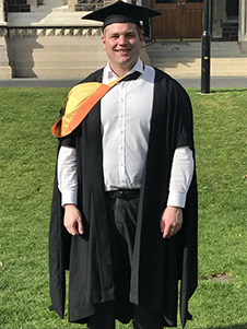 Graduate in front of a clocktower 