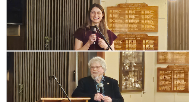 A woman and a man stand and talk using microphones.