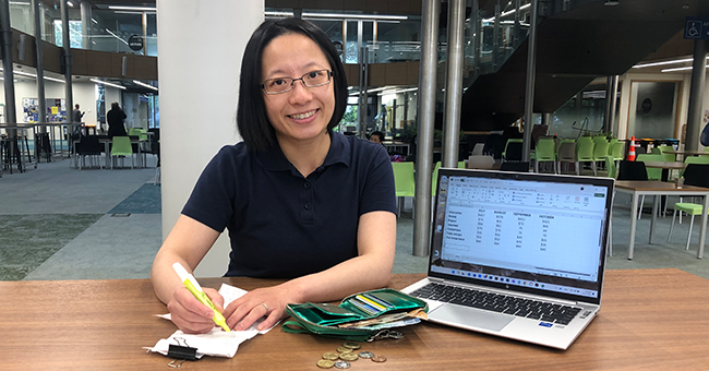 A woman sitting with a laptop. wallet and receipts 