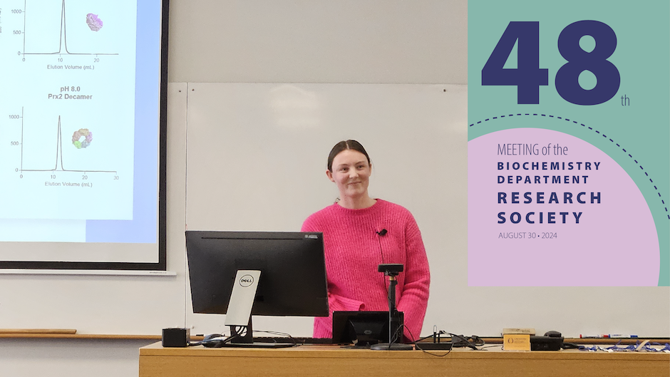 A smiling student stands behind a lectern.