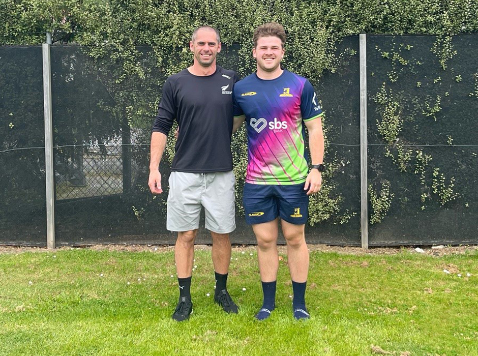 Two men standing next to each other on grass