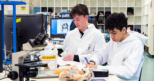 Two medical students writing up report in a lab.