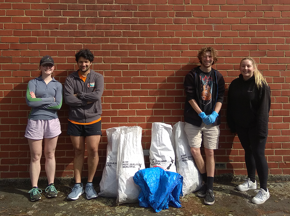 four people standing next to bags full of rubbish