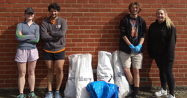 four people standing with bags of rubbish