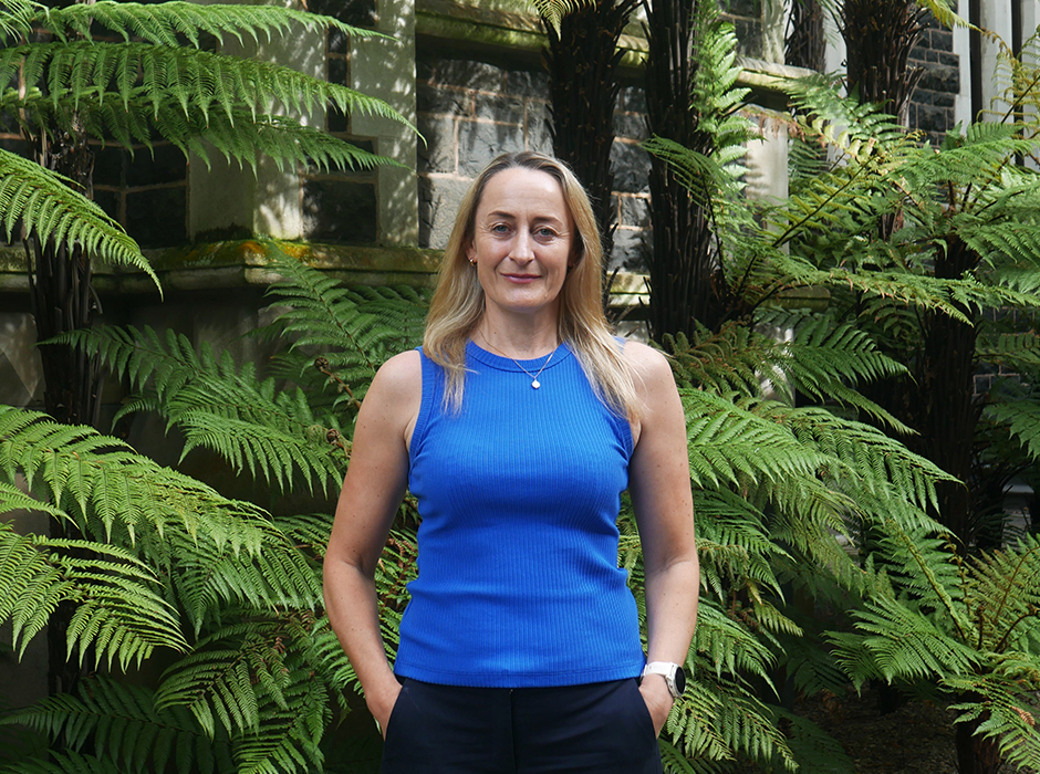 A woman standing in front of greenery