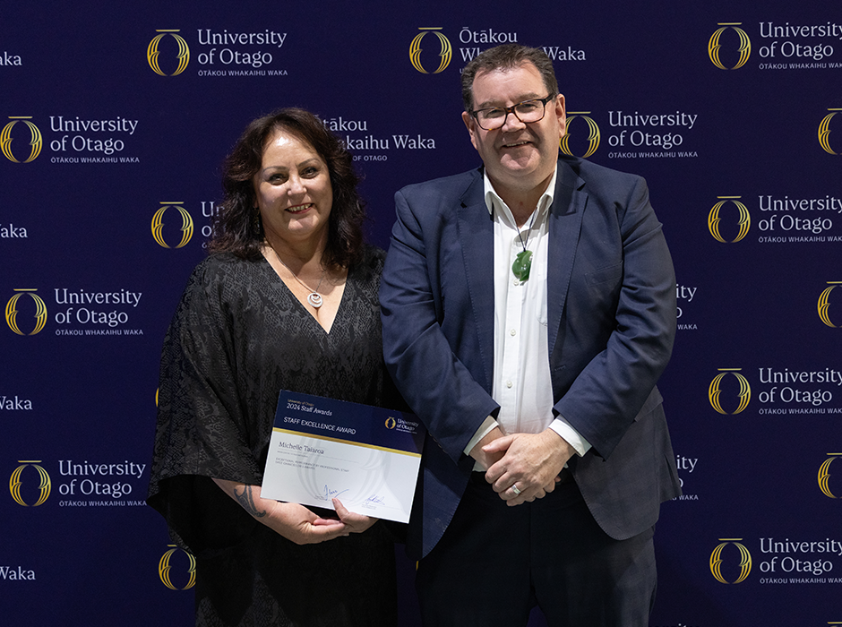 A woman on stage holding an award, standing next to a man 